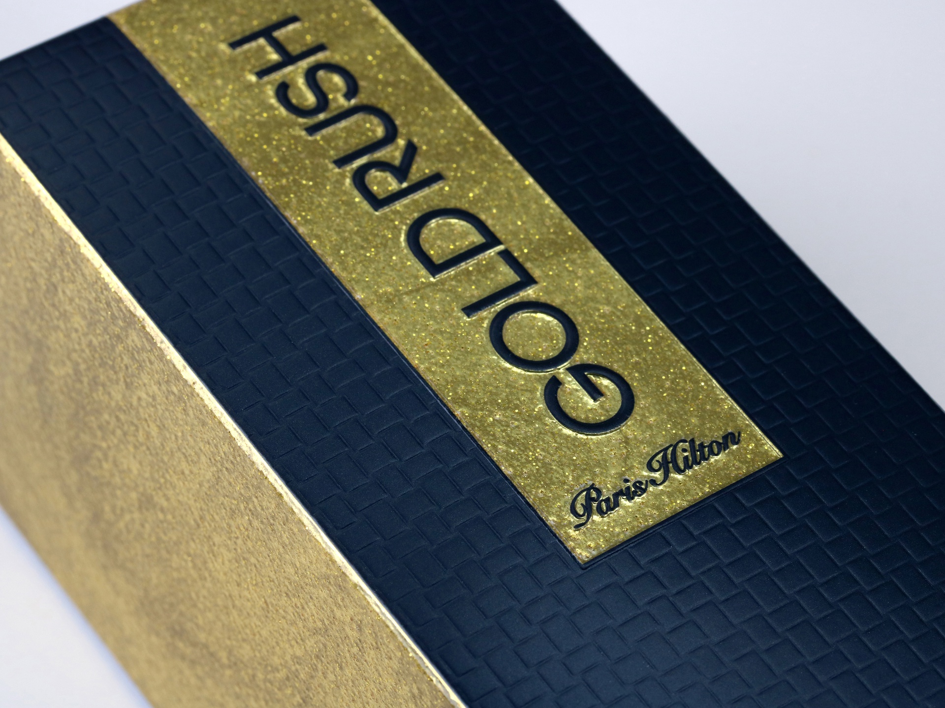 Gold Rush Man Paris Hilton folding cartons feature UV flexo glitter pearl coating and multi-level embossing.